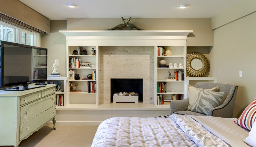 lower level bedroom with fireplace and built-in bookshelf